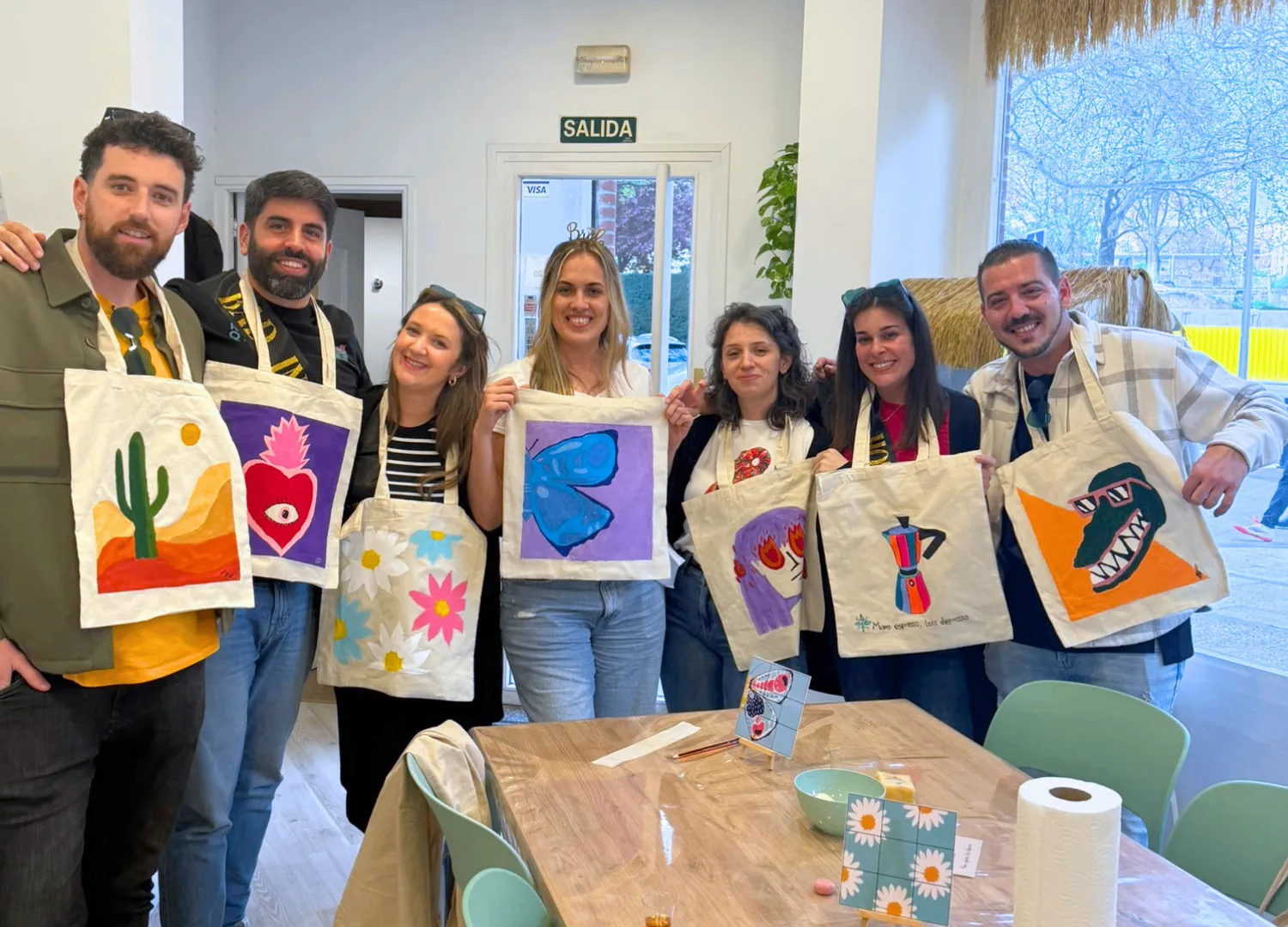 Grupo con totebags pintados mostrando sus diseños en Bungaló